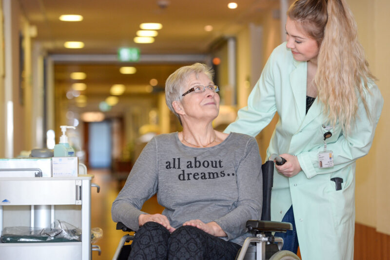 Julia Klink (re.) begleitet eine Patientin im Krankenhaus (Szene nachgestellt). Foto: Schernstein